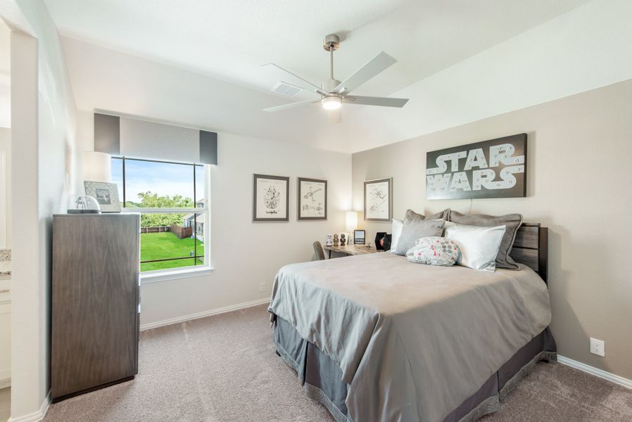Bedroom with gray carpet, ceiling fan, and Star Wars wall art above a queen bed