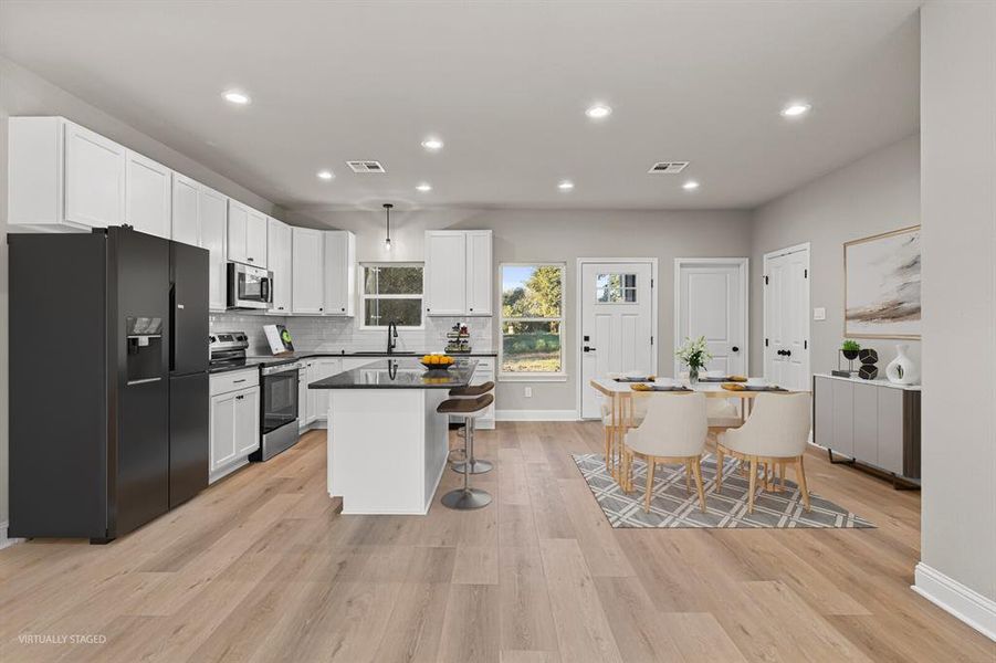 Kitchen featuring appliances with stainless steel finishes, white cabinets, recessed lighting, a kitchen island, and decorative backsplash Kitchen featuring appliances with stainless steel finishes, white cabinets, recessed lighting, a kitchen island, and decorative backsplash