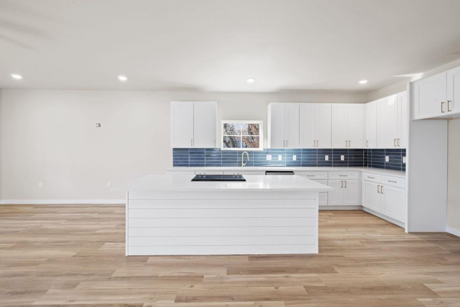 Kitchen featuring white cabinets, backsplash, recessed lighting, light wood finished floors, and a kitchen island Kitchen featuring white cabinets, backsplash, recessed lighting, light wood finished floors, and a kitchen island