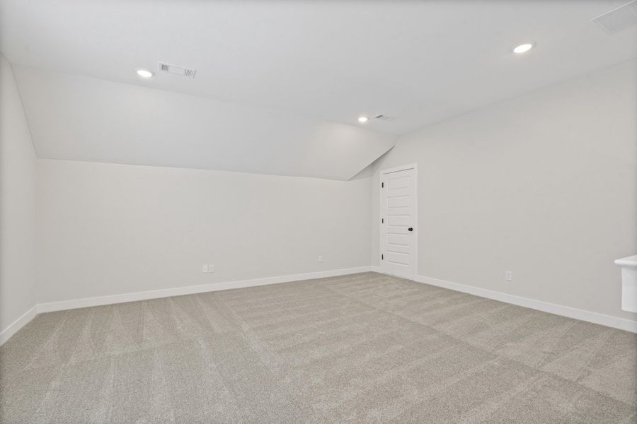 Versatile room featuring sloped ceilings, recessed lighting, and neutral-toned carpeting Versatile room featuring sloped ceilings, recessed lighting, and neutral-toned carpeting