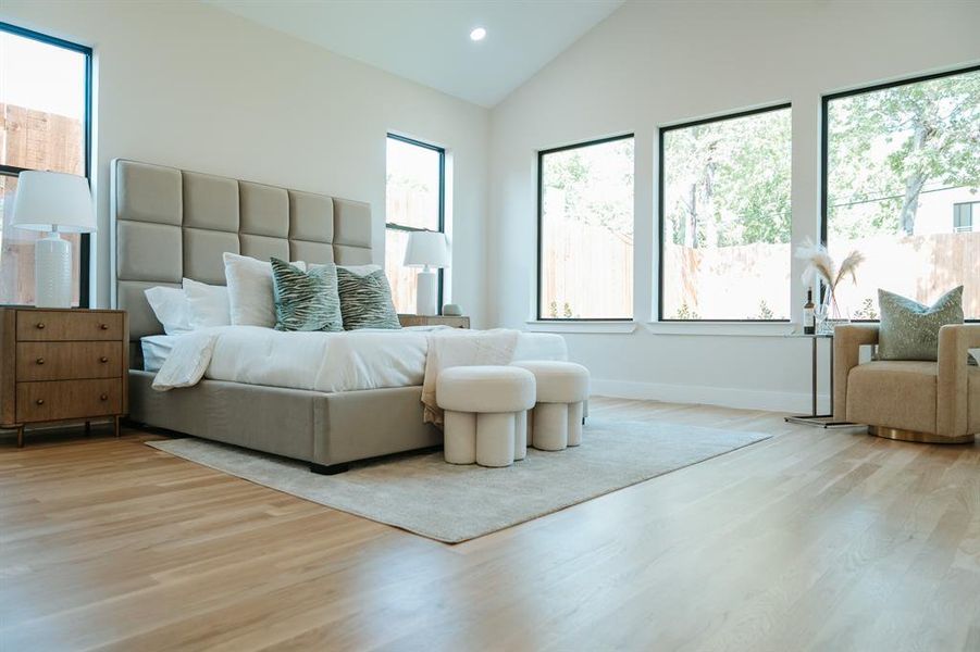 Bedroom with light hardwood / wood-style flooring and high vaulted ceiling