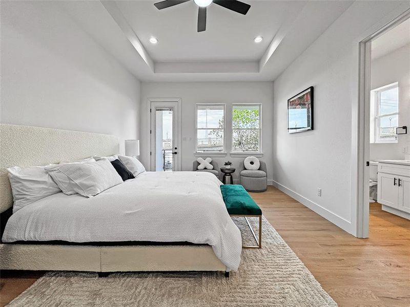 Bedroom featuring light wood finished floors, baseboards, a tray ceiling, ceiling fan, and recessed lighting