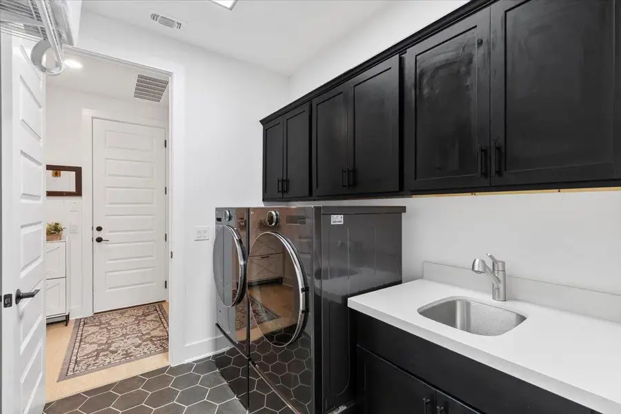 Washroom with cabinet space, independent washer and dryer, and dark tile patterned flooring