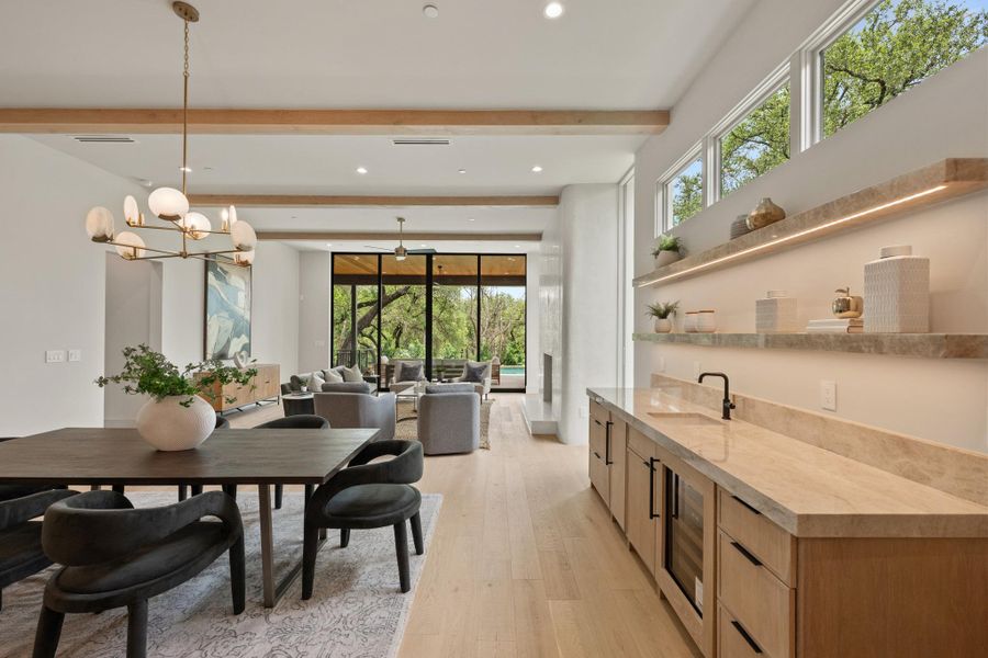 An open-concept living area with soaring ceilings and light wood floors features a stylish wet bar. An open-concept living area with soaring ceilings and light wood floors features a stylish wet bar.