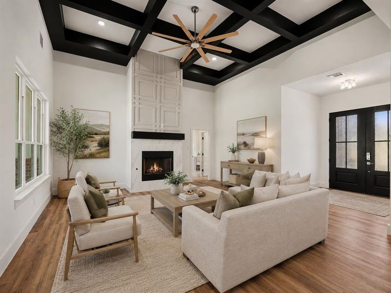 Spacious living area featuring a coffered ceiling with a wood-blade fan, a fireplace with a marble-finish surround, and a decorative paneled accent wall