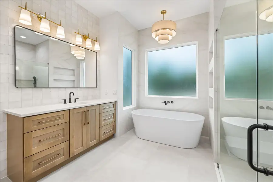Full bath with a freestanding tub, double vanity, tile walls, a shower with shower door, and light tile patterned flooring Full bath with a freestanding tub, double vanity, tile walls, a shower with shower door, and light tile patterned flooring