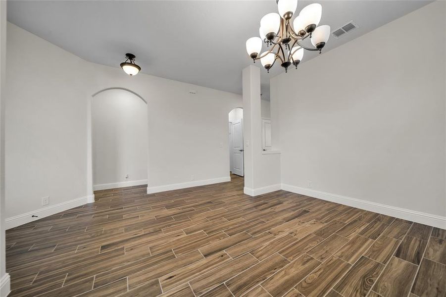 Empty room with arched walkways, wood finish floors, and a chandelier Empty room with arched walkways, wood finish floors, and a chandelier