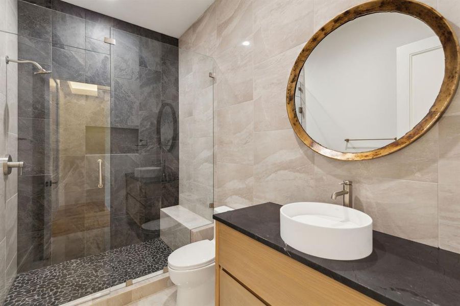 Full bathroom featuring tile walls, a stall shower, and vanity