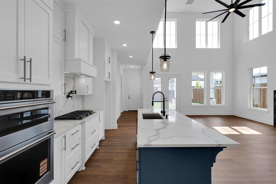 Kitchen featuring stainless steel appliances, dark wood-type flooring, white cabinets, light stone counters, and recessed lighting Kitchen featuring stainless steel appliances, dark wood-type flooring, white cabinets, light stone counters, and recessed lighting
