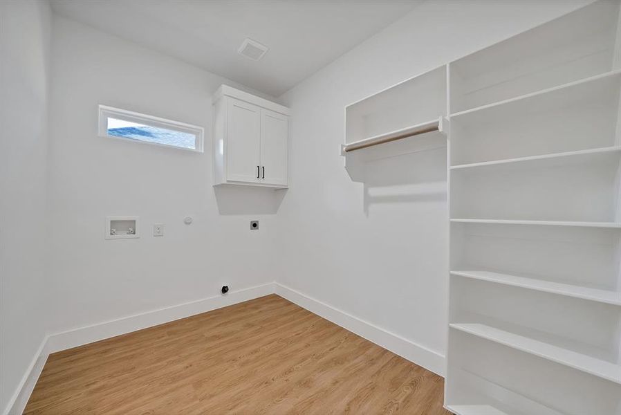 Laundry room featuring hookup for a gas dryer, light wood finished floors, hookup for a washing machine, electric dryer hookup, and cabinet space