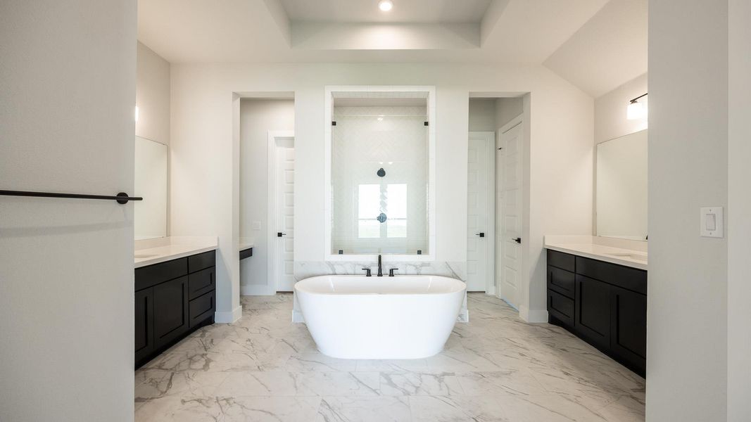 Bathroom with two vanities, a soaking tub, a walk in shower, and light marble finish floors Bathroom with two vanities, a soaking tub, a walk in shower, and light marble finish floors