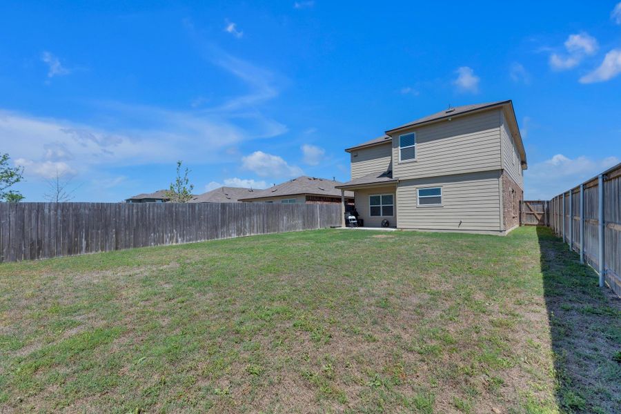 Rear view of property featuring a fenced backyard and a lawn