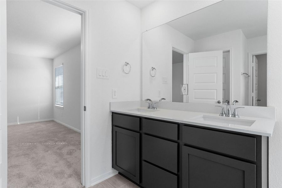 This stunningly updated primary bathroom is truly move-in ready! It features stained cabinetry with light countertops, dual sinks, a large mirror, a generous walk-in closet with built-in shelving, soaring ceilings, custom paint, and sleek modern finishes throughout.