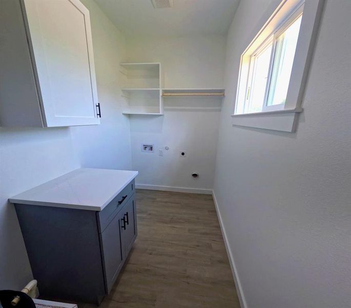 Laundry area with hookup for a washing machine, light wood-style floors, electric dryer hookup, cabinet space, and gas dryer hookup Laundry area with hookup for a washing machine, light wood-style floors, electric dryer hookup, cabinet space, and gas dryer hookup