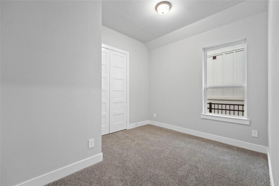 This secondary bedroom features high sloped ceiling, custom paint, plush carpet, large window, and an ample sized closet space!