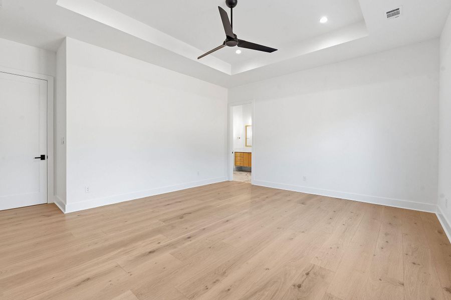 Clean lines and warm wood floors define this elegant, light-filled primary suite.