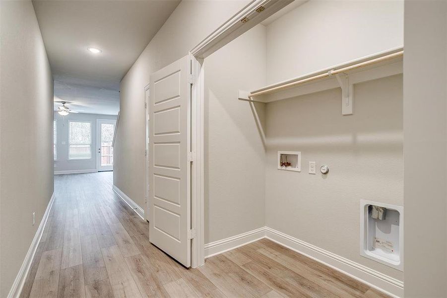 Laundry room with baseboards, laundry area, light wood-type flooring, and hookup for a gas dryer