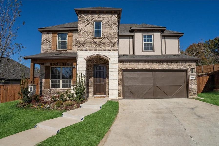 View of front facade featuring a garage and a front lawn