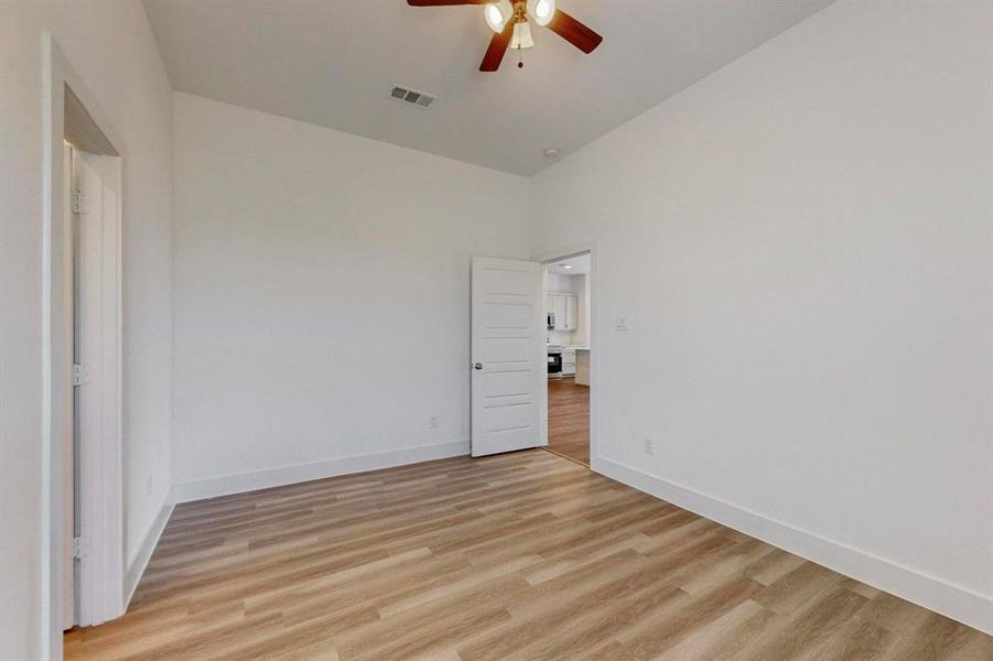 Unfurnished room featuring a high ceiling, ceiling fan, and light wood-type flooring