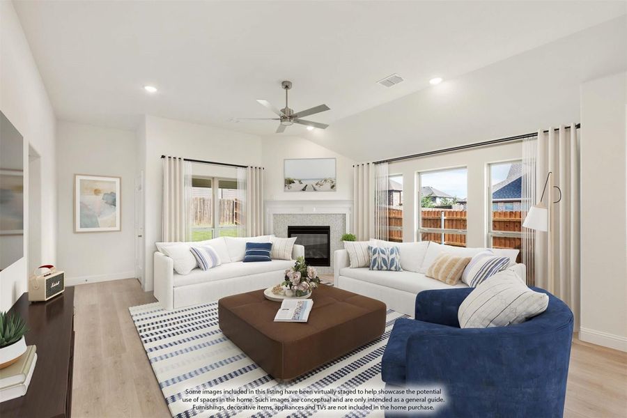 Bright living room with vaulted ceiling, ceiling fan, fireplace, and large windows overlooking backyard