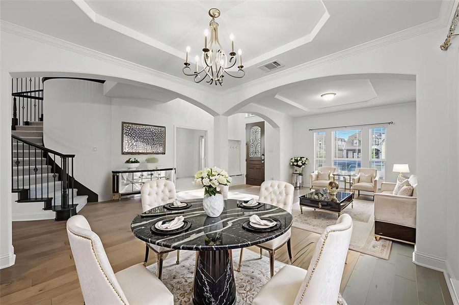 Dining space with a raised ceiling, arched walkways, stairs, crown molding, and wood finished floors Dining space with a raised ceiling, arched walkways, stairs, crown molding, and wood finished floors