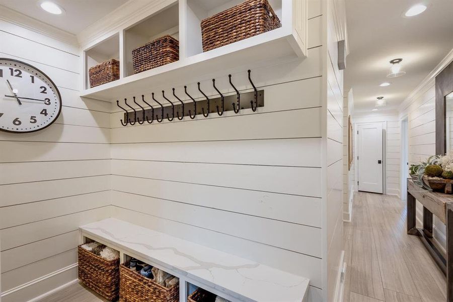 Mudroom with ornamental molding, light wood-type flooring, and wooden walls