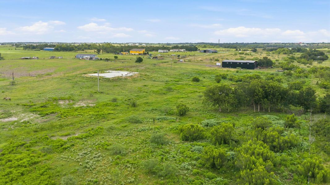 An aerial perspective reveals the verdant landscape and scattered rural structures under a broad sky.