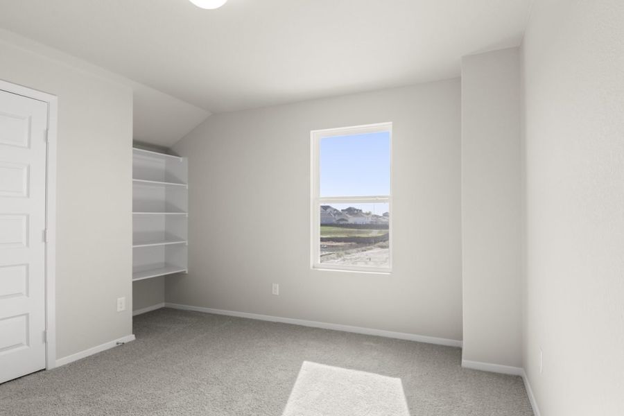 Image of a bedroom with light grey walls, tan carpeting, and a window
