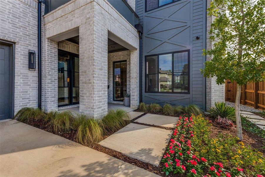 Modern exterior featuring light-colored brick, dark panel siding, and a covered entryway with a black framed glass door Modern exterior featuring light-colored brick, dark panel siding, and a covered entryway with a black framed glass door