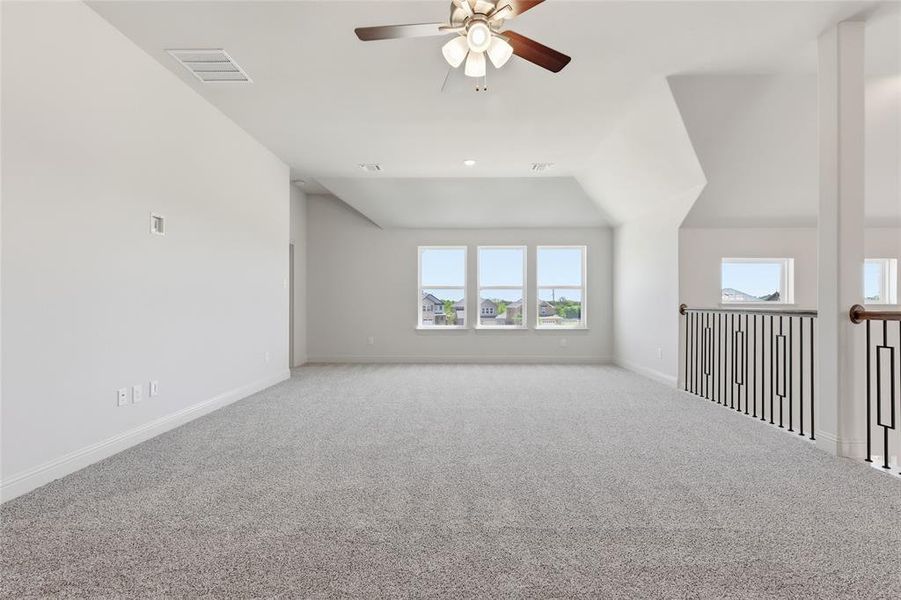 Carpeted spare room with a ceiling fan and lofted ceiling