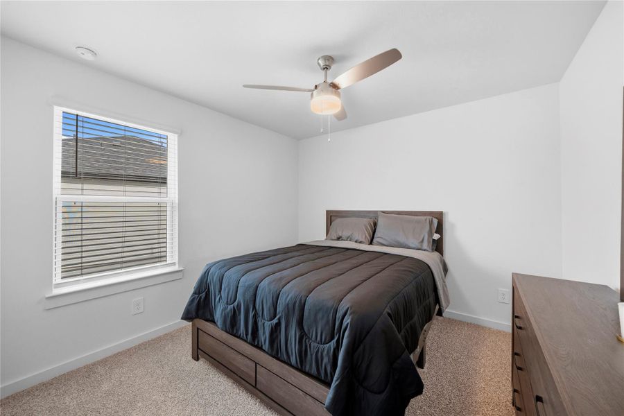This third bedroom features a streamlined design with neutral tones, a sunlit window, and a ceiling fan, creating a comfortable and inviting space. This third bedroom features a streamlined design with neutral tones, a sunlit window, and a ceiling fan, creating a comfortable and inviting space.
