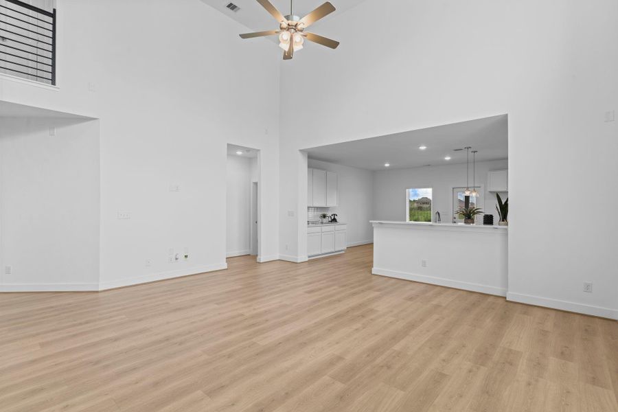 Another view of the light-filled family room highlights the effortless transition to the kitchen and dining areas, all tied together with wood-like tile flooring and modern finishes. **Image Representative of Plan Only and May Vary as Built**.