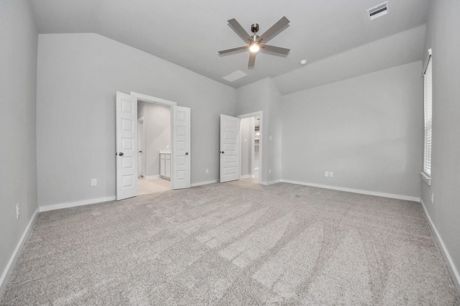 Escape and relax in the exquisite primary suite, a haven to unwind after a long day. The spacious room, located on first floor, boasts plush carpeting, soothing paint tones, high ceilings, and expansive windows adorned with privacy blinds.