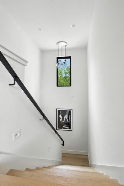 Stairs featuring wood finished floors and a chandelier Stairs featuring wood finished floors and a chandelier