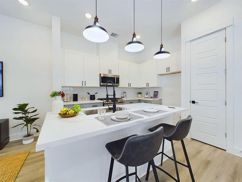 This attractive kitchen is full of beautiful details. Quartz countertops, stainless steel sink, stainless steel appliances, recessed lighting, undercabinet lighting, pantry, elegant cabinetry with soft close drawers and doors. Photos from another development by Disama Building Group. FINISHES & COLORS MAY VARY.