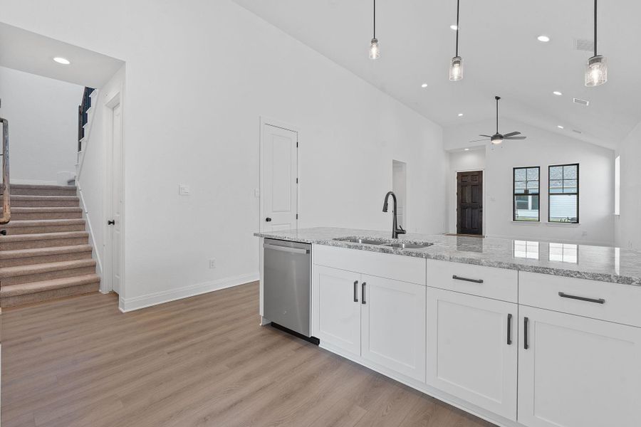 Kitchen with recessed lighting, white cabinetry, light stone counters, hanging light fixtures, and light wood-type flooring Kitchen with recessed lighting, white cabinetry, light stone counters, hanging light fixtures, and light wood-type flooring