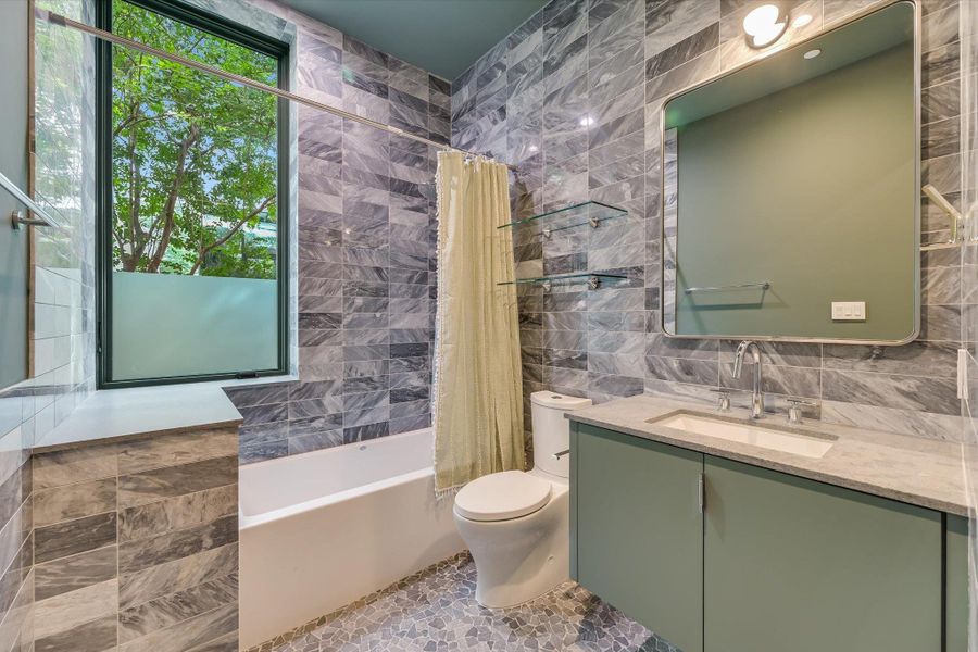 Full bath featuring tile walls, vanity, and shower / bathtub combination with curtain