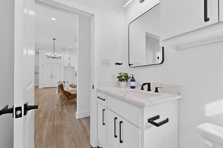Half bath featuring vanity, light wood-style flooring, a chandelier, and recessed lighting