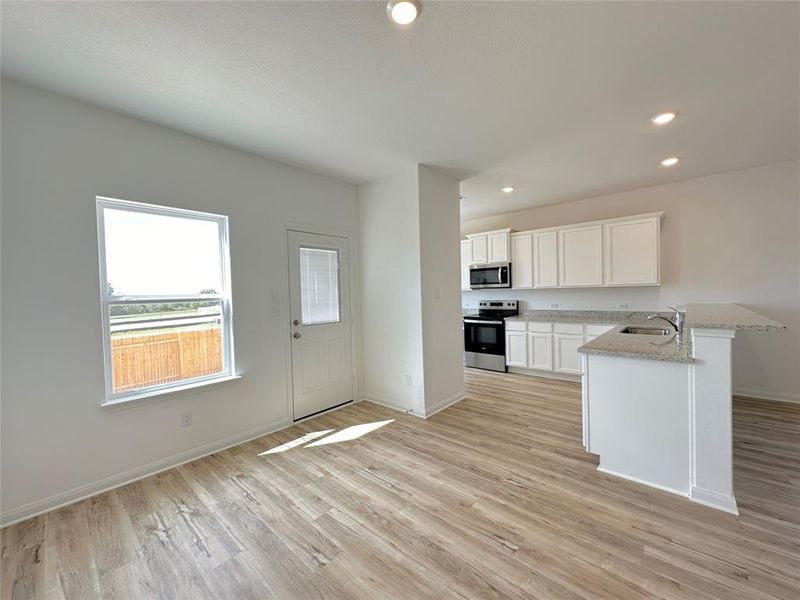 Kitchen includes granite countertops, luxury vinyl plank flooring, 36” upper cabinets with crown molding, a full suite of stainless-steel Whirlpool appliances – including refrigerator with ice maker, recessed lighting, and a large single basin sink.