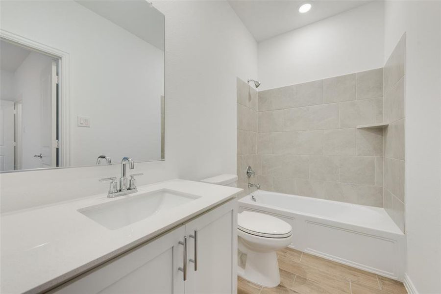 Full bathroom with tile patterned flooring, vanity, tiled shower / bath combo, and toilet