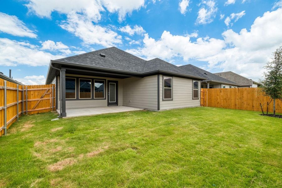 A spacious backyard with a private fence, lush green lawn, and a covered patio for outdoor enjoyment.