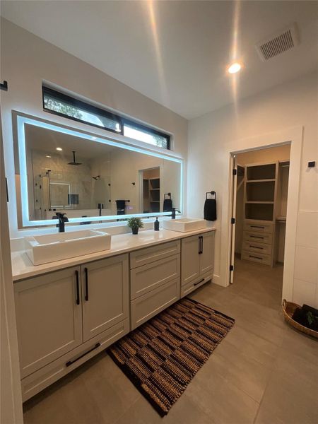 Bathroom featuring a walk in closet, a shower stall, double vanity, and light tile patterned floors Bathroom featuring a walk in closet, a shower stall, double vanity, and light tile patterned floors
