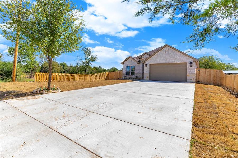 View of front facade with concrete driveway, brick siding, and an attached garage