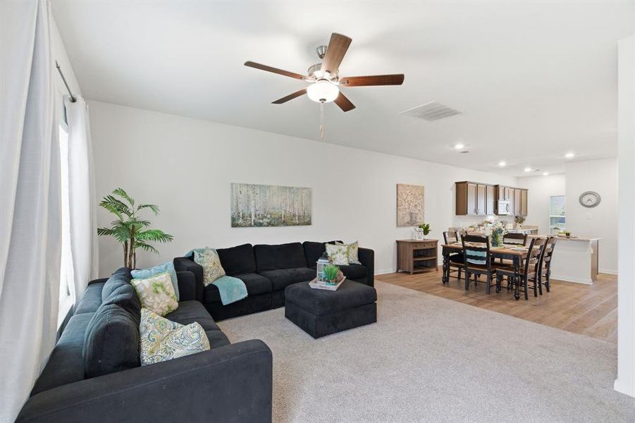 Open concept living area with light-colored carpeting, a ceiling fan, and recessed lighting