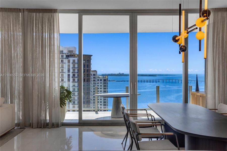 Floor-to-ceiling glass sliding doors, polished tile flooring, balcony with glass railing, and modern multi-bulb statement lighting