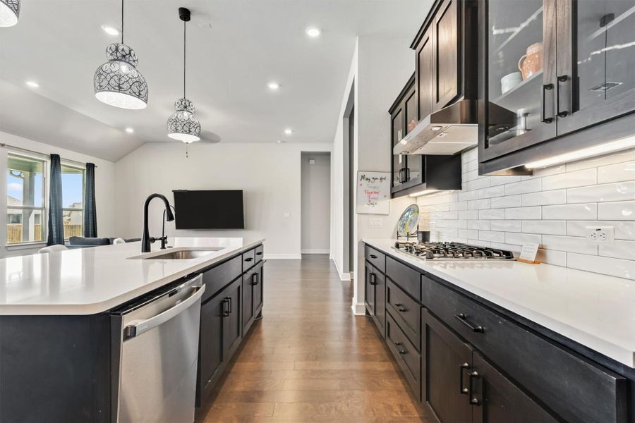 Kitchen with glass insert cabinets, decorative light fixtures, stainless steel appliances, recessed lighting, and wood finished floors Kitchen with glass insert cabinets, decorative light fixtures, stainless steel appliances, recessed lighting, and wood finished floors
