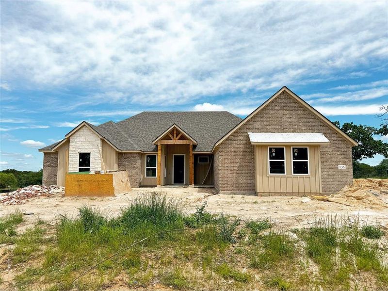 Unfinished property with roof with shingles, board and batten siding, and stone siding