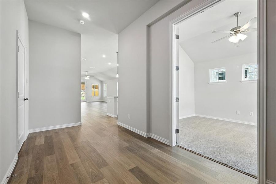 Hall featuring plenty of natural light, lofted ceiling, wood finished floors, and recessed lighting Hall featuring plenty of natural light, lofted ceiling, wood finished floors, and recessed lighting