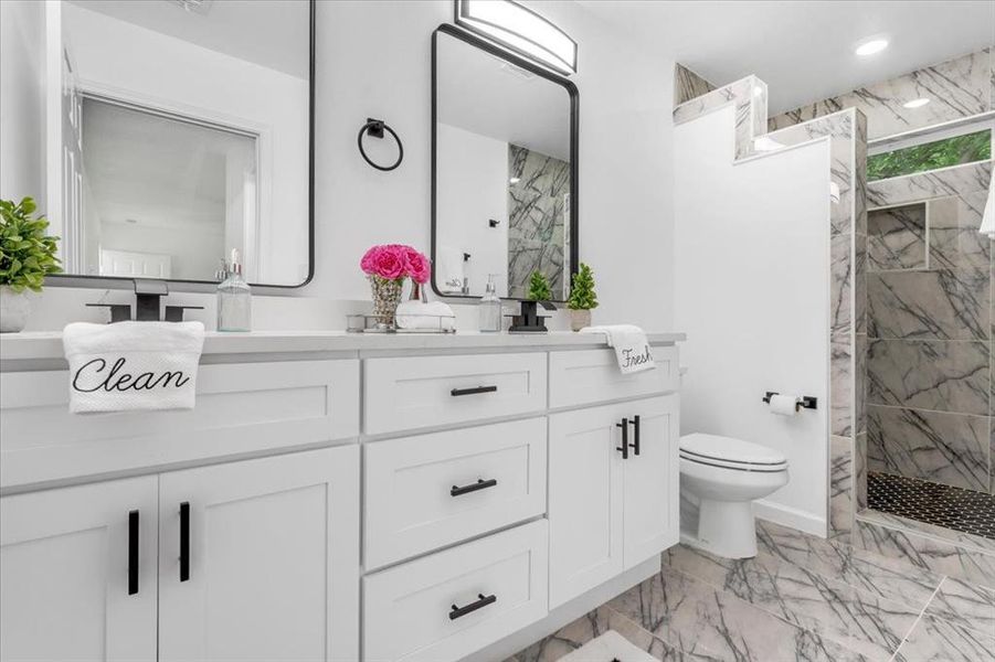 Bathroom featuring tile patterned flooring, toilet, a tile shower, and double vanity