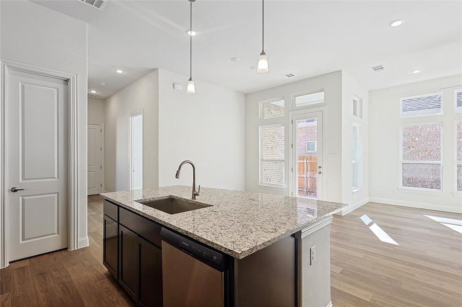 Kitchen with dishwasher, a wealth of natural light, hanging light fixtures, and sink